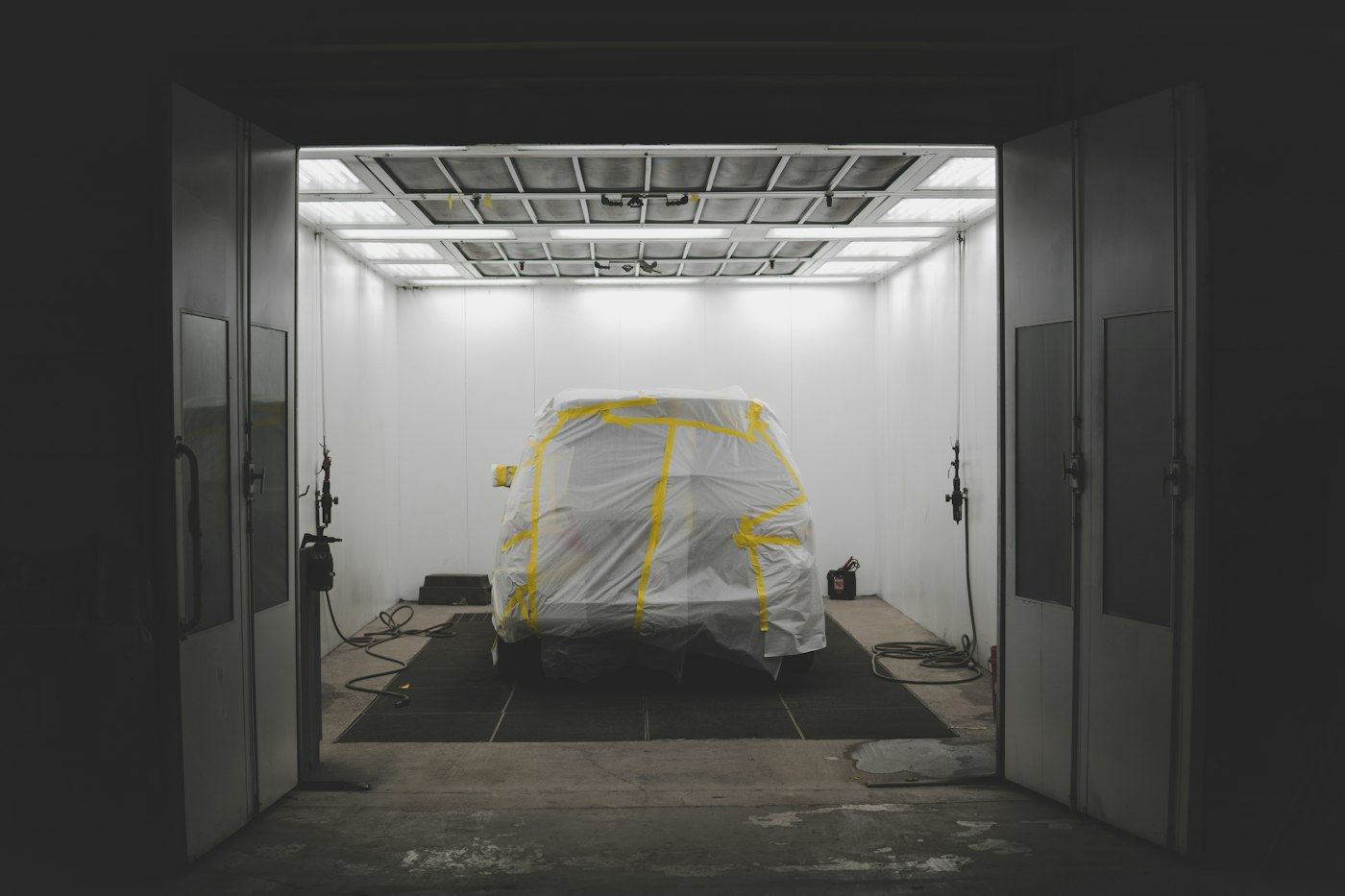 A vehicle covered in protective masking in the workshop